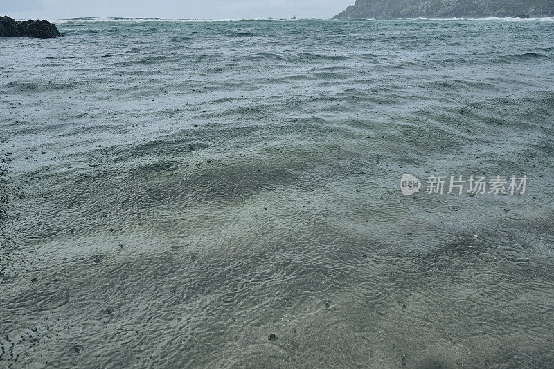 六月阴沉沉的一天，康沃尔的佩德旺德海滩海面上下着大雨。