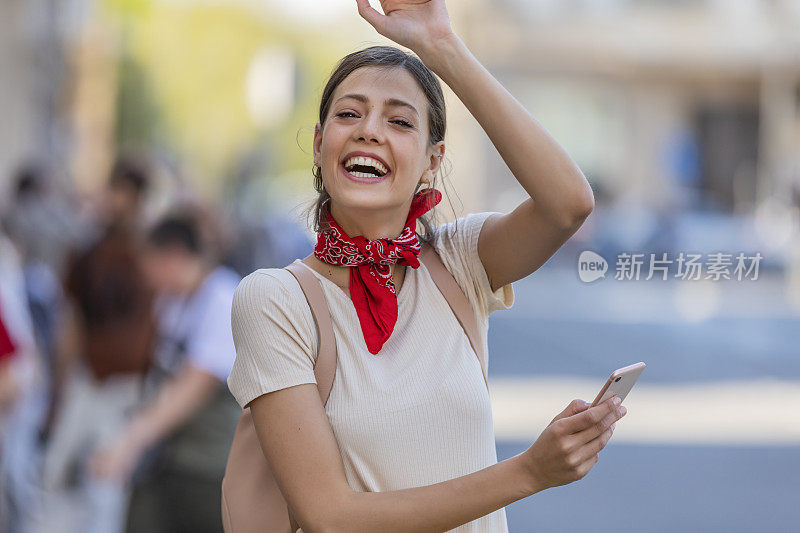 一名年轻女子正带着她的智能手机走在城市的路上