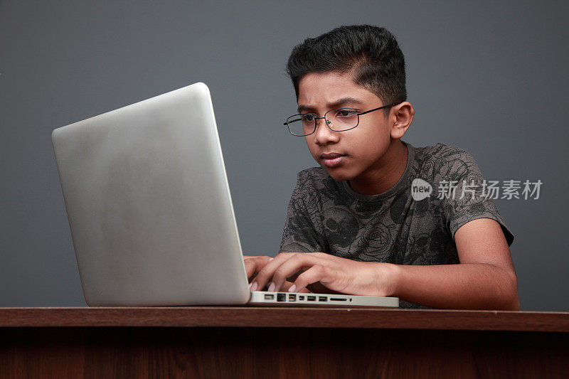 一个小男孩在用笔记本电脑