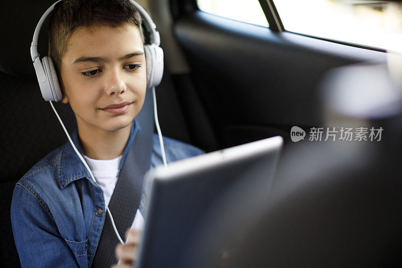 十几岁的男孩在车里用平板电脑