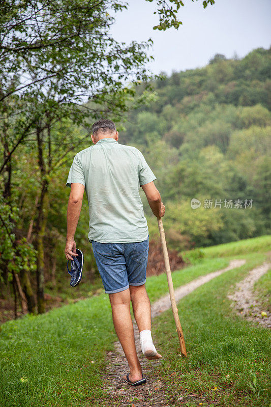 一个成年男子扭伤了脚踝，走在乡间小路上