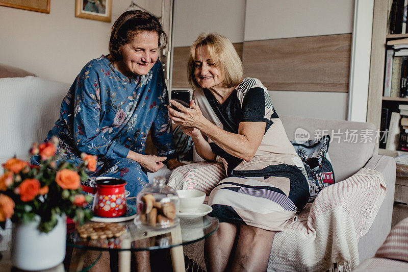 两位年长女性在家里使用智能手机