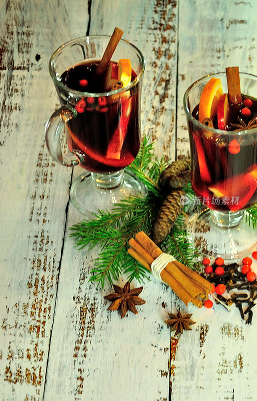 桌上放着两杯加了水果和香料的热红酒，周围是冷杉树枝和松果。
