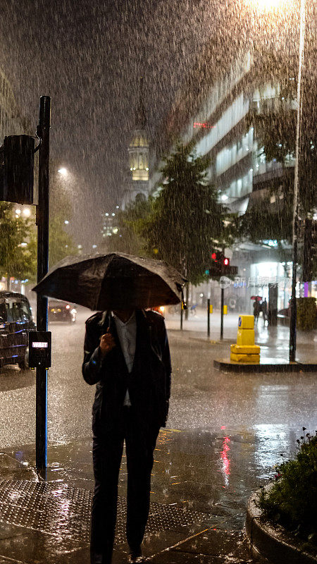 在下雨的伦敦街道上，一个男人撑着雨伞