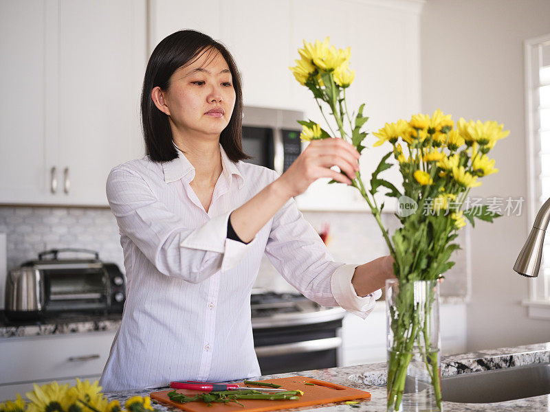 亚洲妇女在她的家里插花