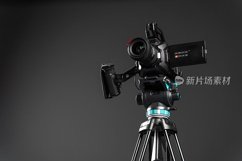 专业的视频影院摄像机上的相机三脚架上的黑色背景复制空间