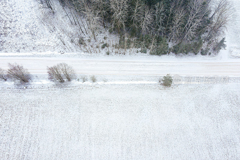冬天雾蒙蒙的乡间小路和白雪覆盖的田野。鸟瞰图