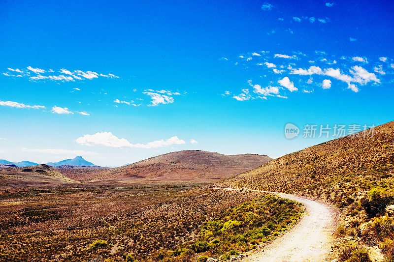 在南非卡鲁半沙漠地带，土路蜿蜒穿过崎岖干旱的景观