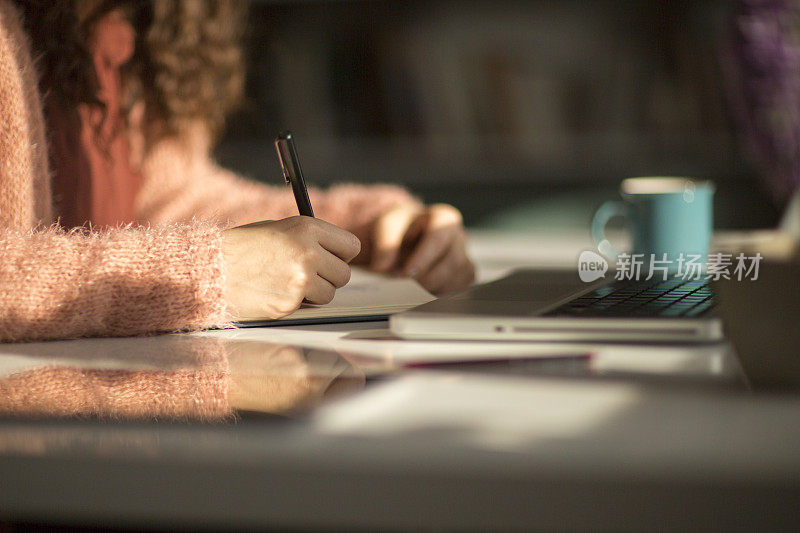 一个女人的手在笔记本电脑上忙着打字的特写