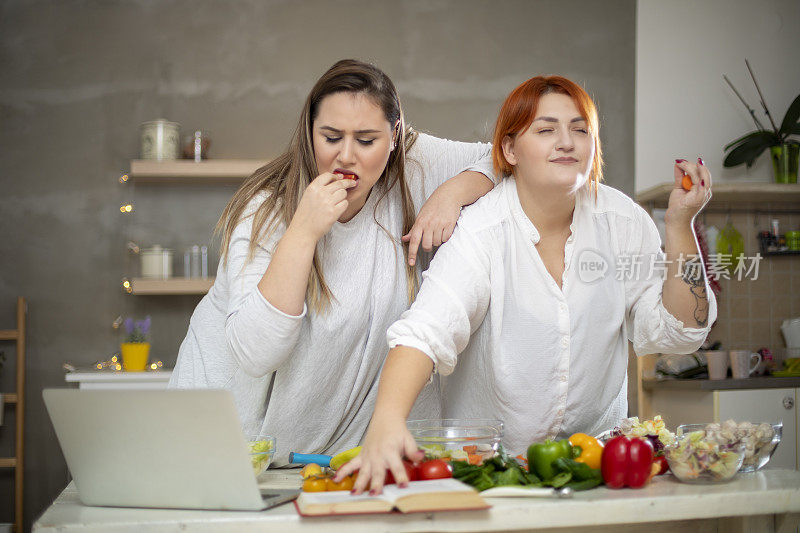 年轻微笑的胖女人用笔记本电脑准备早餐。