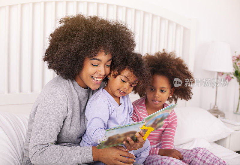 母亲和女儿们在床上看书