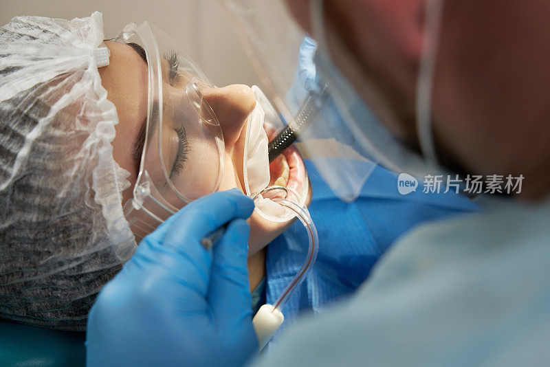 牙医在牙科椅上给男病人钻孔