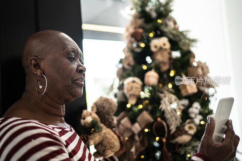 一位高级女士在用智能手机进行视频通话并向会议同事展示圣诞树