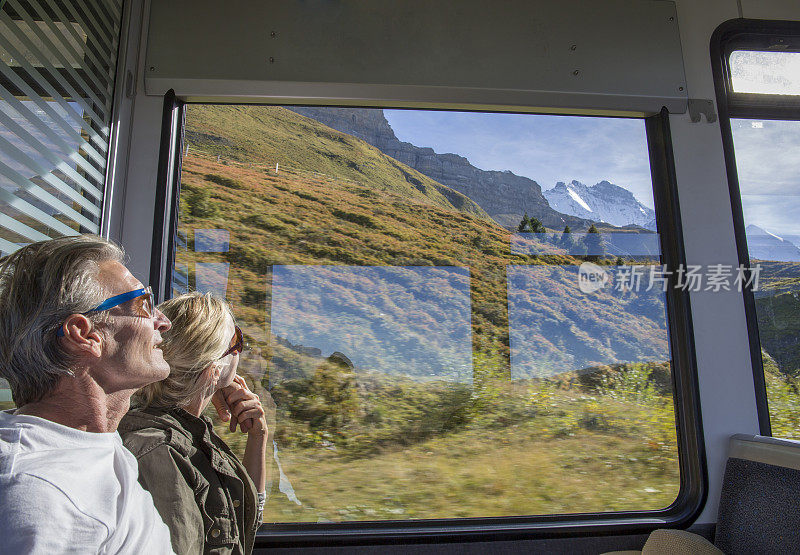 一对成熟的夫妇在行驶的火车上欣赏路过的风景