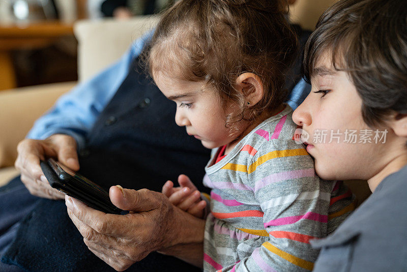 爷爷、孙子在用智能手机看电影
