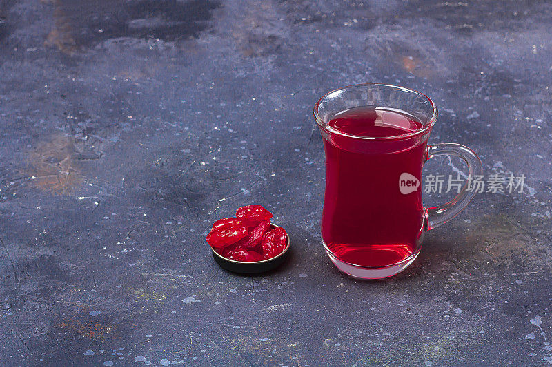 土耳其茶杯(armudu)红茶(roibos，木槿，karkade)和干果(山茱萸)在深色的背景上。草药，维生素，治疗感冒和流感的排毒茶。关闭，为文本复制空间
