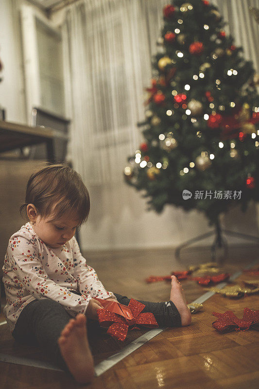 可爱的小女孩坐在地板上玩圣诞装饰品