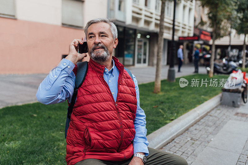 一个成熟的男人在城里打电话，休息一下