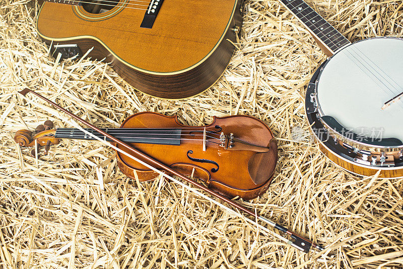 收藏的乐器躺在稻草，完美的乡村音乐:吉他，小提琴和班卓琴