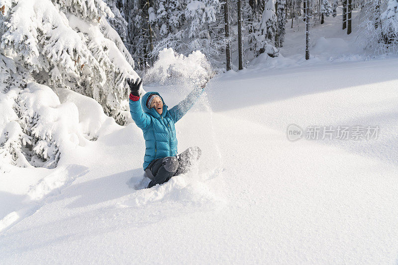 在冬天的森林里，成熟的女人穿着皮大衣向空中抛雪