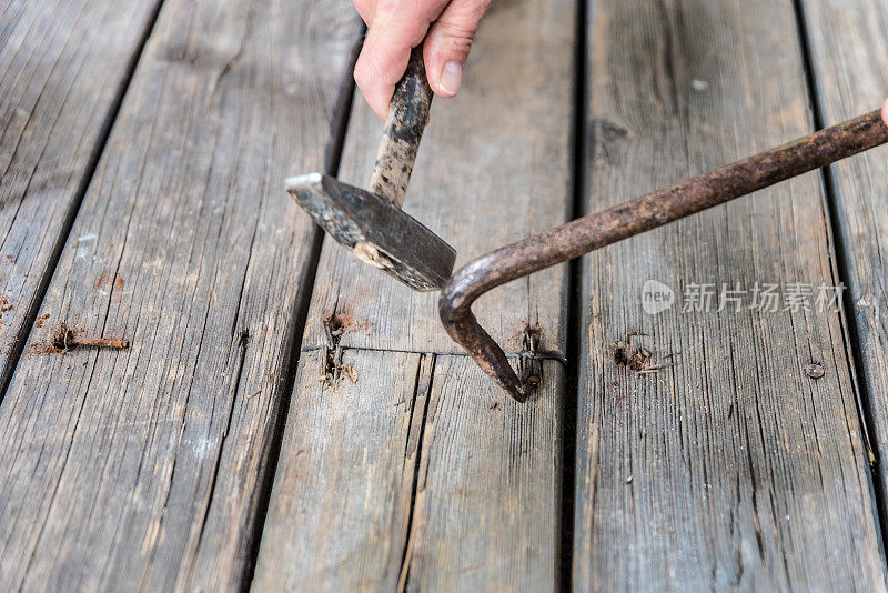 男子用撬棍取出钉子，从阳台上取出旧木板