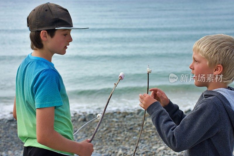 男孩们在海滩边吃煮棉花糖