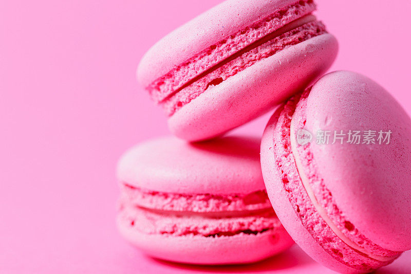 堆三个粉红色的杏仁饼干，粉红色的填充在粉红色的背景