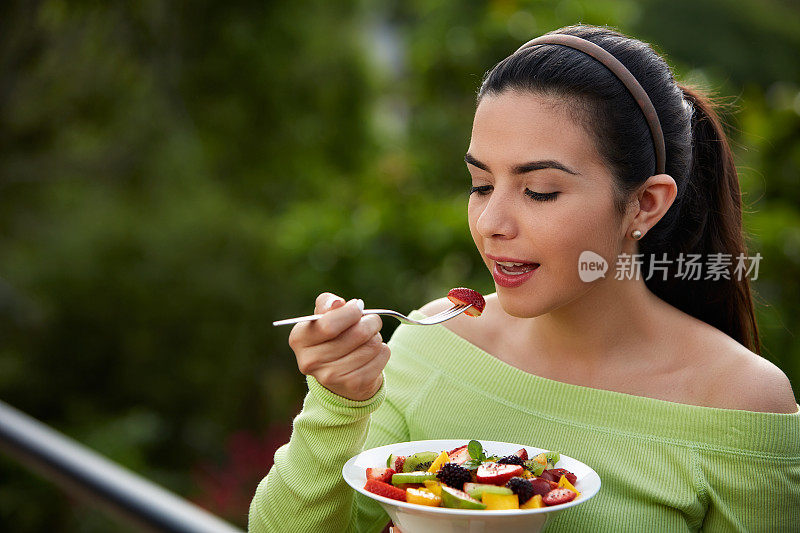 一个西班牙可爱的年轻女子在午餐吃素食沙拉的特写