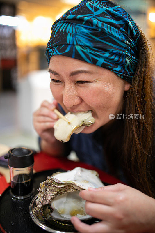 一个女人正在吃一个巨大的新鲜牡蛎