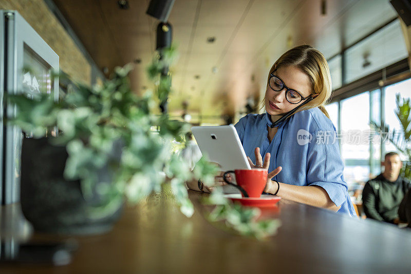 一个非常有魅力的年轻女商人正在Café享受热饮，并在她的手机对话中制定一些商业计划。