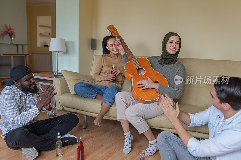 快乐的一群年轻的多元文化朋友在一起度过美好的时光，享受原声吉他的声音。