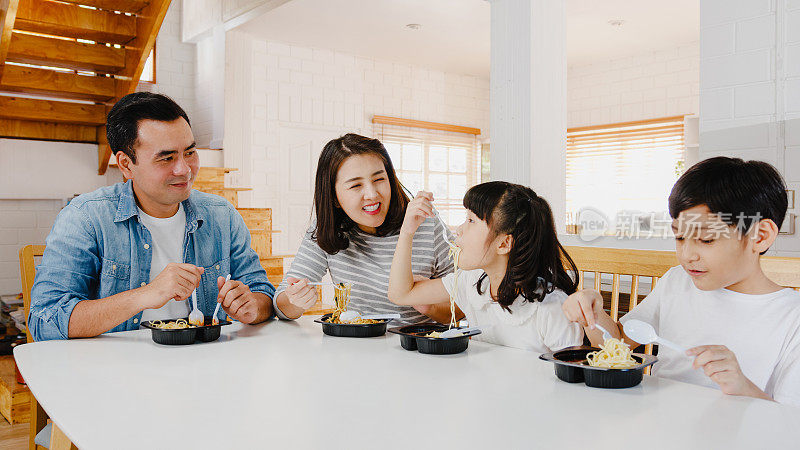 幸福快乐的亚洲家庭在现代家庭的餐厅吃意大利面塑料容器意大利面。