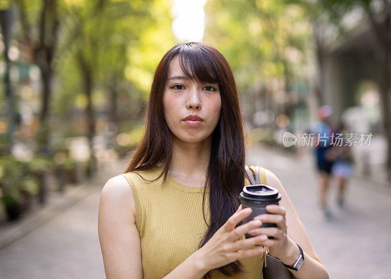 一名身穿黄色衣服的日本女子站在城市街道中央的肖像