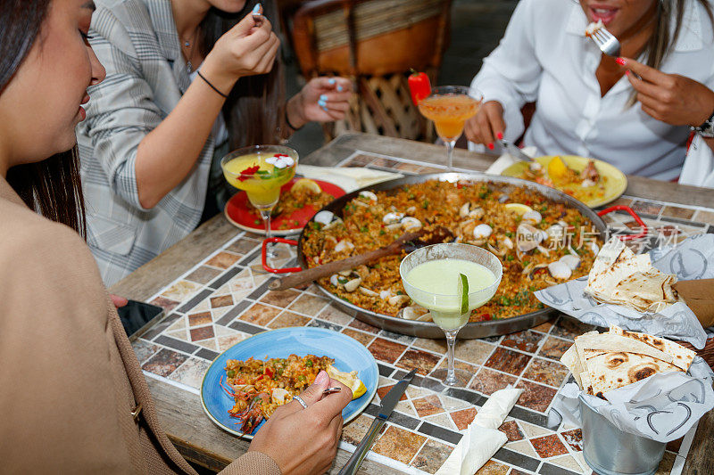 年轻女性在户外餐厅的餐桌上吃着海鲜饭