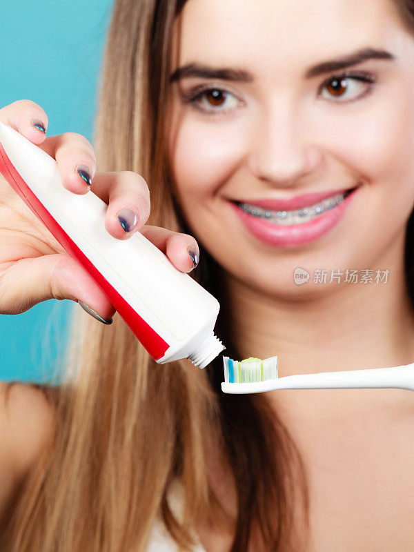 戴牙套的女人拿着牙刷和牙膏