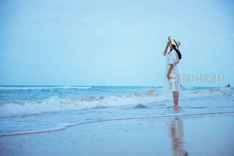 年轻女子站在沙滩上望着大海