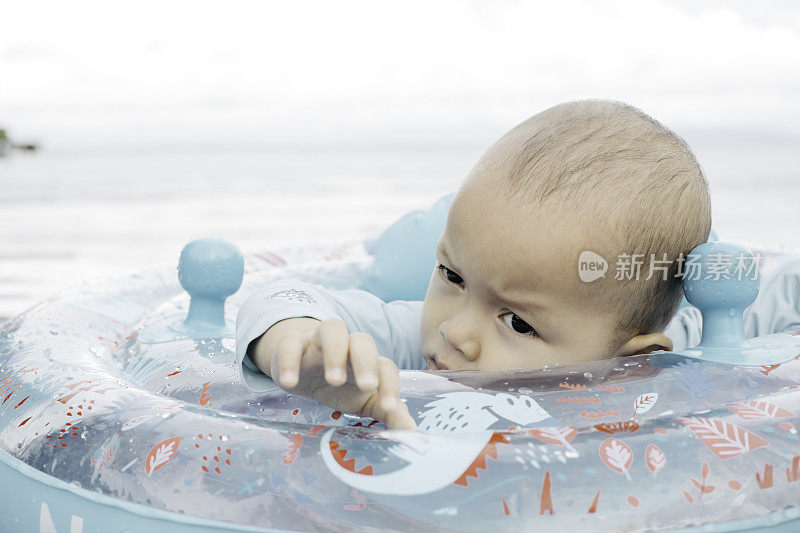 亚洲婴儿睡在游泳池的浮标上
