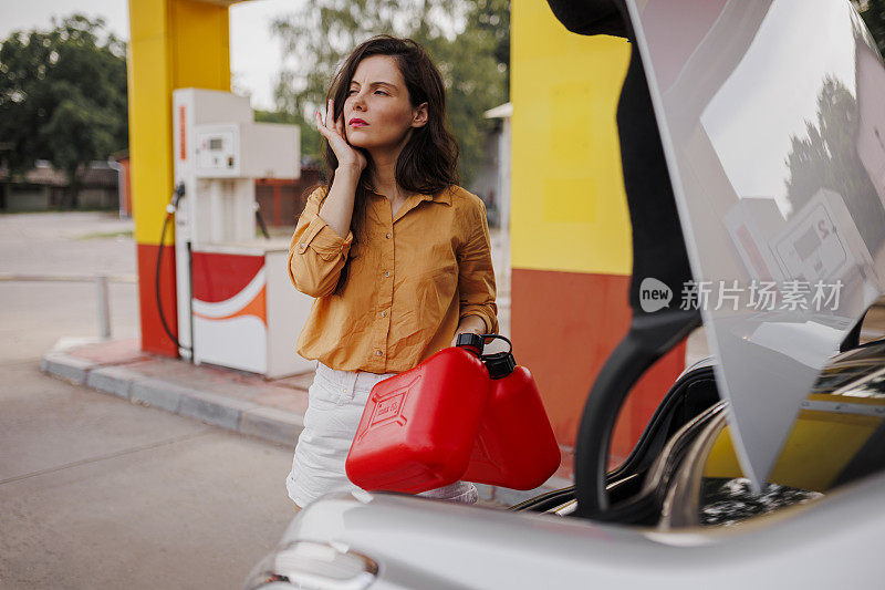 焦虑的女人在加油站拿着油罐
