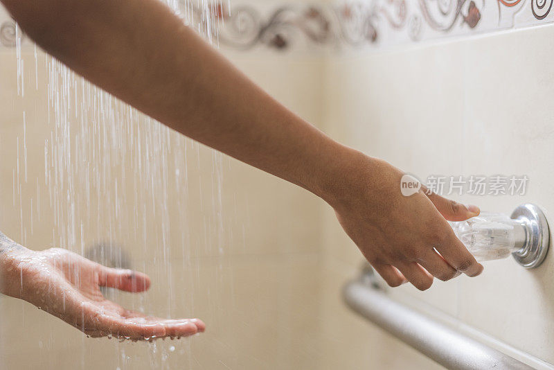 这位拉丁妇女正在自家的浴室里用手试水的热度