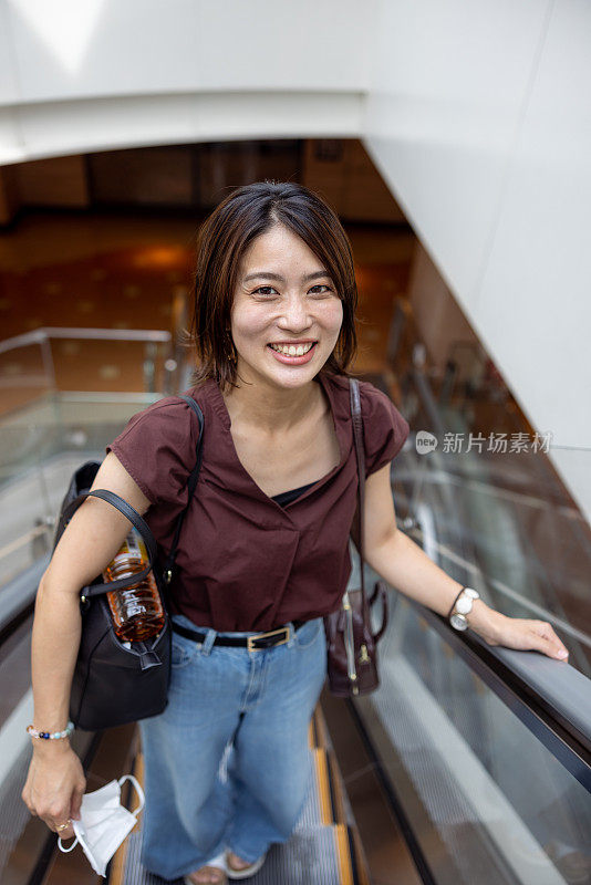 一个女人在机场的自动扶梯上往上走