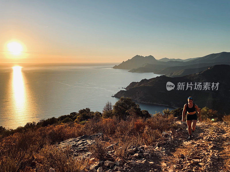 清晨，年轻女子在海边的山坡上奔跑