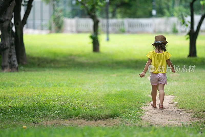 幼儿园小女孩在公园散步的后照