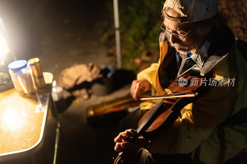一个年长的人在营地拉小提琴