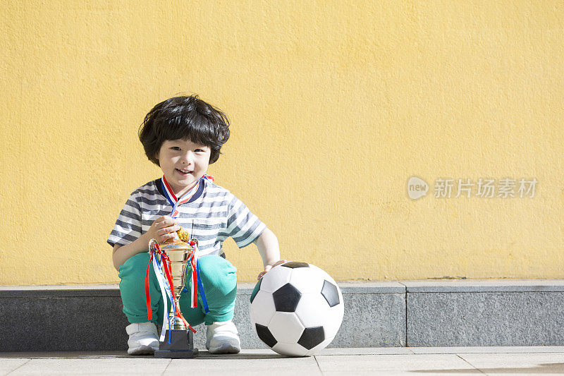 赢得足球锦标赛的小男孩和他的奖杯——库存照片
