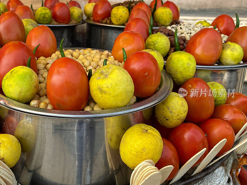 全帧图像的街头食品准备在户外烤箱顶部不锈钢烹饪锅，泡米饭与西红柿，柠檬和青辣椒，重点在前景