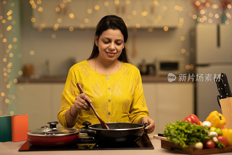 印度妇女在厨房做饭时享受的肖像。库存图片