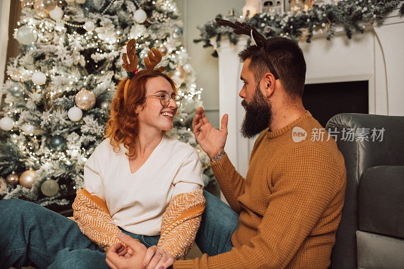 一对可爱的夫妇坐在圣诞树前