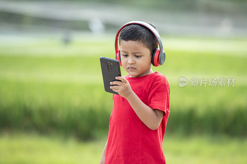 蹒跚学步的男孩用耳机听音乐