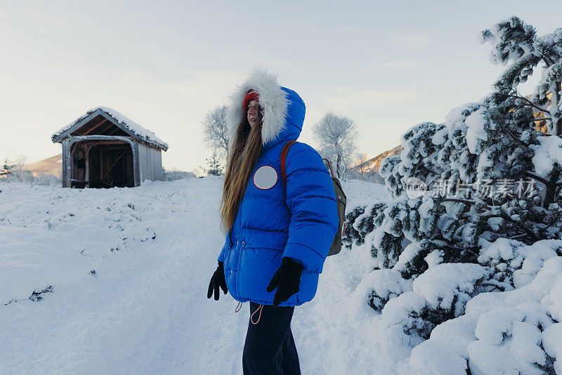 挪威，一名女子走在通往收容所的雪道上，凝视着寒冷的冬日