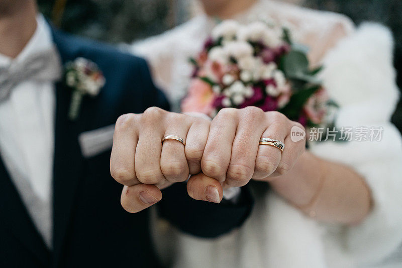 新娘和新郎在他们的拳头上展示结婚戒指